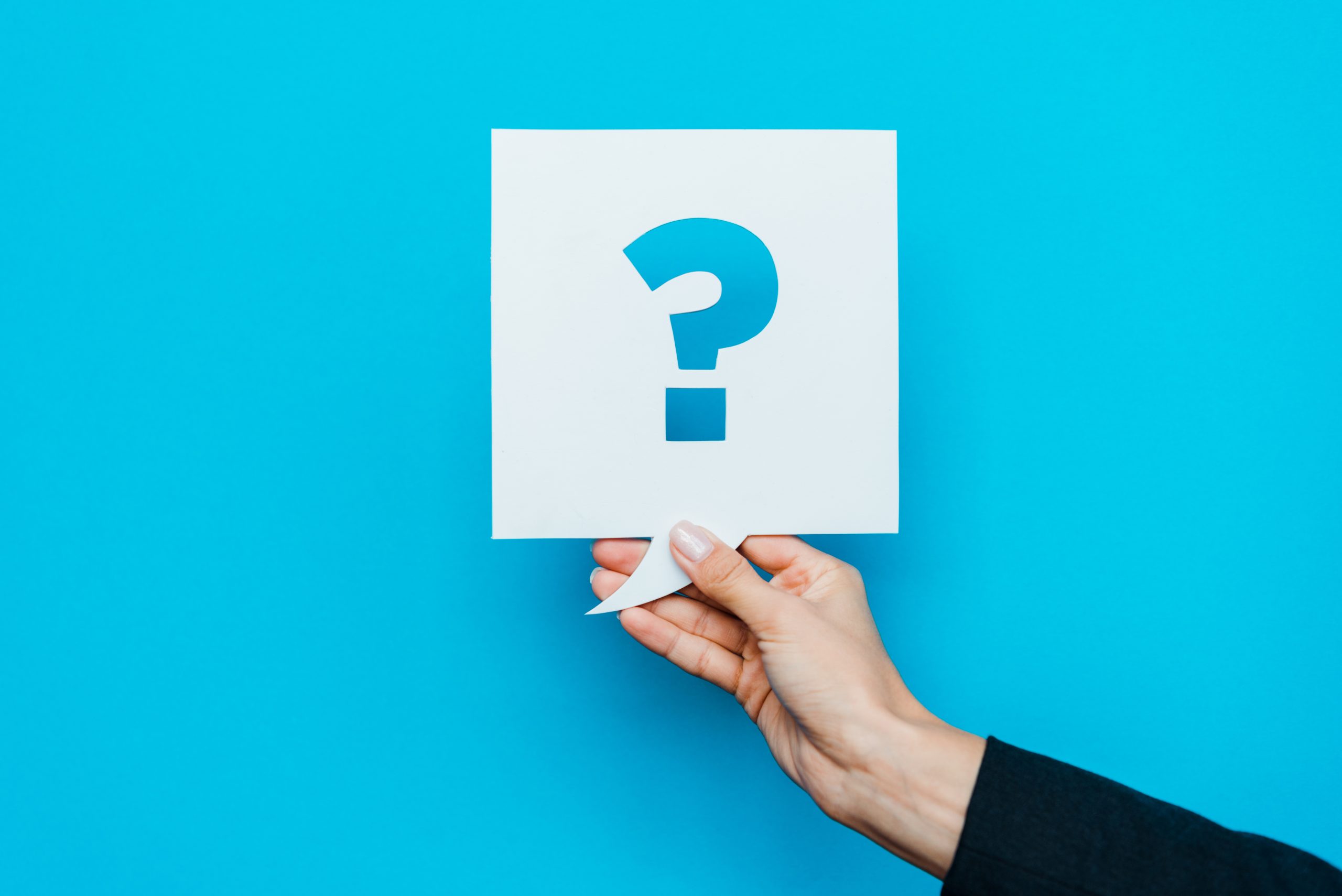 cropped view of woman holding speech bubble with question mark on blue